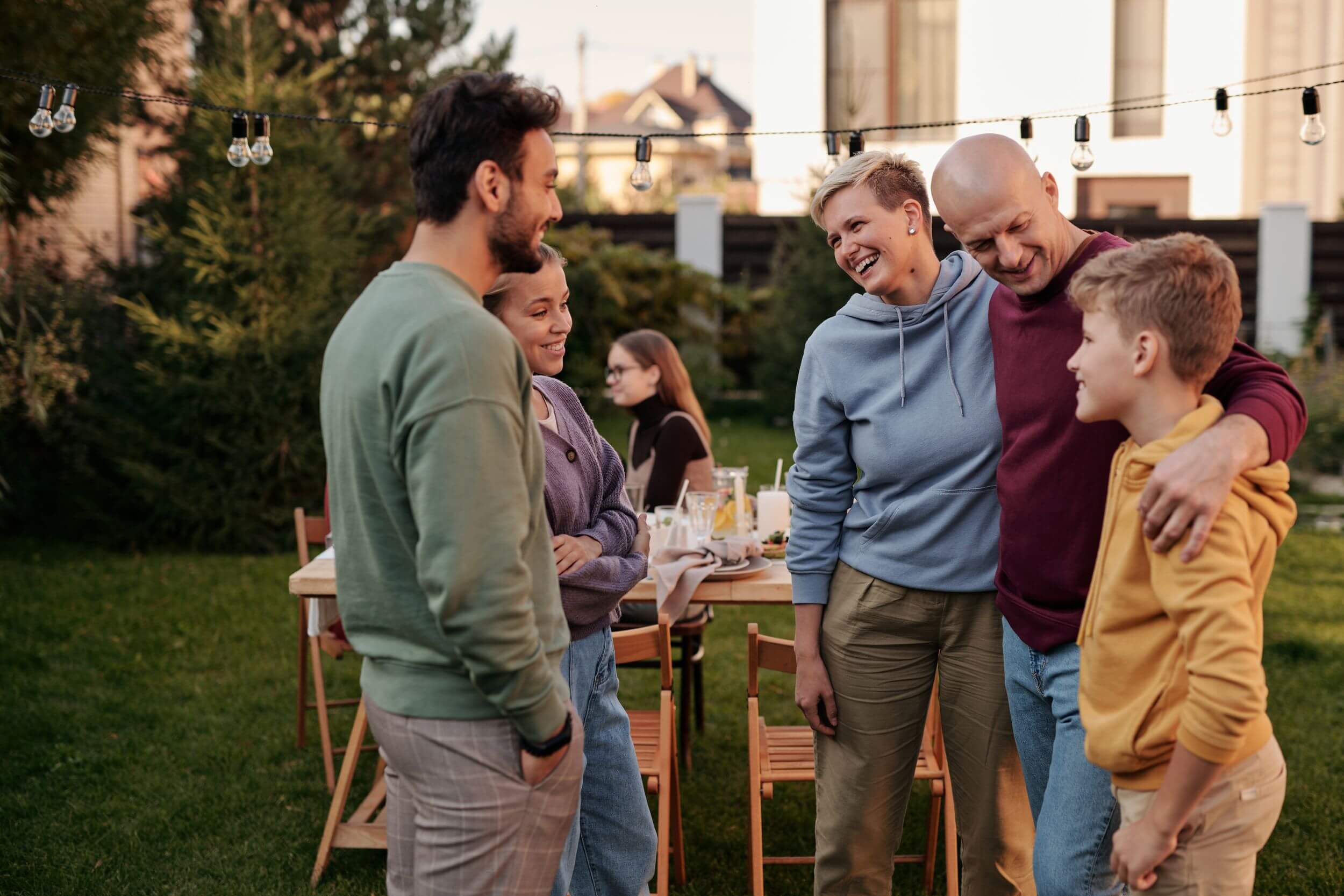 Family smiling and talking in their green backyard.